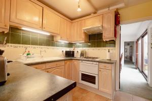 a kitchen with wooden cabinets and a stove top oven at Palm Bay's Luxury Bungalow - Self Check In & Parking in Margate