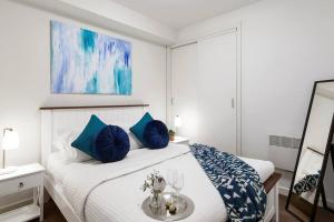 ein weißes Schlafzimmer mit einem Bett mit blauen Kissen in der Unterkunft Gem in the heart of South Yarra in Melbourne