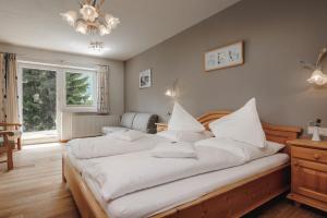 a bedroom with two beds with white sheets and a chandelier at Hotel Rotlechhof in Berwang