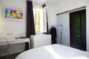 a bedroom with a white bed and white walls at Hôtel Les 3 Terrasses in Sari Solenzara