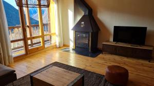 a living room with a fireplace and a television at Boí Taüll CALMA DÚPLEX in Taüll