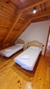 two beds in a room with a wooden ceiling at Boí Taüll CALMA DÚPLEX in Taüll