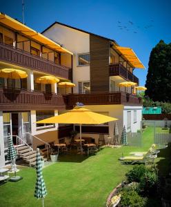 ein Gebäude mit Tischen und Sonnenschirmen im Hof in der Unterkunft Kurhotel Wiedenmann in Bad Wörishofen
