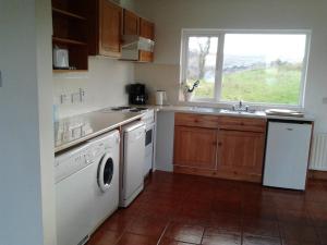 een keuken met een wasmachine en droger en een raam bij Betty's Cottage in Ardea
