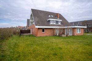 a brick house with a roof on a green yard at Deichlamm in Sankt Peter-Ording