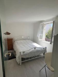 ein weißes Schlafzimmer mit einem Bett und einem Fenster in der Unterkunft Maison Ancienne à côté des Champs Elysees in Puteaux