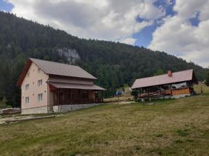 a building in a field next to a mountain at Cabana Colț de Rai in Arieşeni