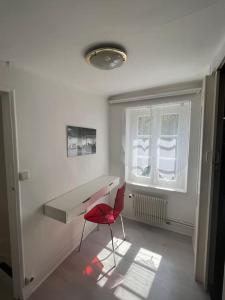 Dieses weiße Zimmer verfügt über einen Schreibtisch und einen roten Stuhl. in der Unterkunft Maison Ancienne à côté des Champs Elysees in Puteaux