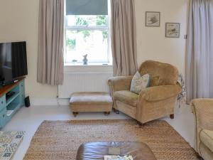 a living room with two chairs and a television at Greenwood Cottage in Longframlington