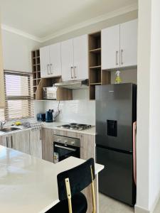 a kitchen with white cabinets and a black refrigerator at Zanaya Apartments in Gaborone