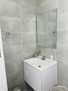 uma casa de banho com um lavatório branco e um espelho. em Zanaya Apartments em Gaborone