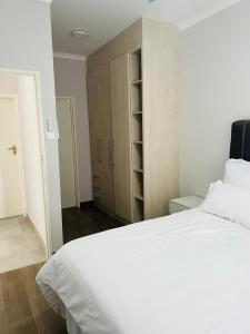 a bedroom with a large white bed and wooden cabinets at Zanaya Apartments in Gaborone