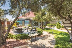 a patio with chairs and tables under a tree at La Quinta by Wyndham Las Vegas Summerlin Tech in Las Vegas