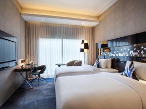 a hotel room with two beds and a television at Novotel Singapore On Stevens in Singapore