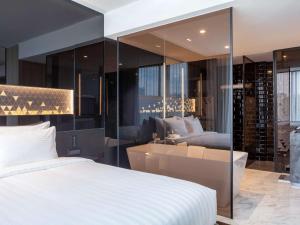 シンガポールにあるノボテル シンガポール オン スティーブンスのベッドルーム1室(ベッド1台付)、リビングルームが備わります。