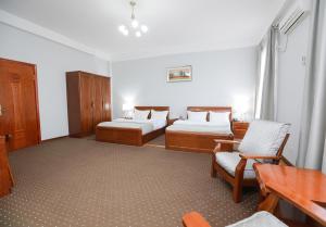um quarto com duas camas e uma mesa e cadeiras em Khujand Grand Hotel em Khujand
