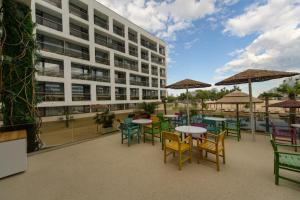 a patio with tables and chairs and a building at Hotel Terra in Neptun