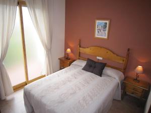a bedroom with a large white bed with two lamps at Casa María Jesús in Pórtugos