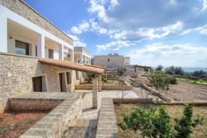 una vista esterna di una casa con l'oceano sullo sfondo di Villetta Madrigale San Gregorio a Patù