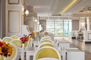 um restaurante com mesas brancas, cadeiras amarelas e flores em Ramada Resort By Wyndham Kizkalesi em Kizkalesi