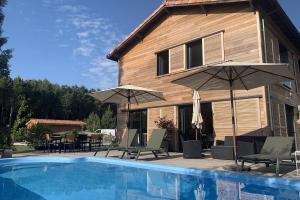 a house with a swimming pool and umbrellas at La Grange du Coulin in Onesse-et-Laharie