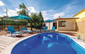 a swimming pool with chairs and umbrellas next to a house at House Antoine in Kras