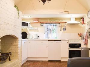 a kitchen with white cabinets and a brick wall at Beck Gate in Alburgh