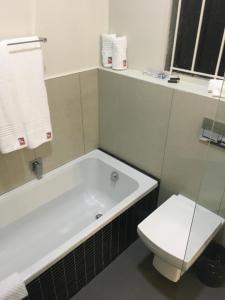 a bathroom with a bath tub and a toilet at The Travel Inn Durban in Durban