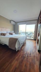 1 dormitorio con 1 cama grande y suelo de madera en Departamento Caseros Salta en Salta
