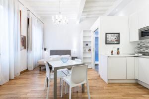 een witte keuken en een eetkamer met een tafel en stoelen bij Emanuele's house in Florence