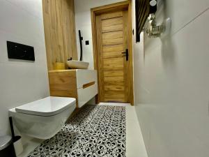 a bathroom with a toilet and a wooden door at Domek Góralski na Ubocy z jacuzzi in Białka Tatrzanska