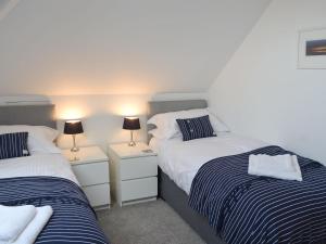 two beds in a room with two lamps on tables at Penfose Apartment in Mevagissey