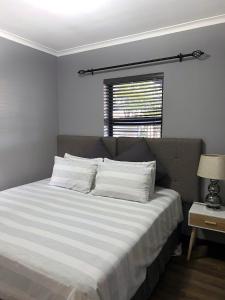 1 dormitorio con 1 cama con sábanas blancas y ventana en 81 on Groenewoud en Ciudad del Cabo