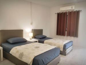 um quarto com 2 camas e uma janela em บ้านในสวนรีสอร์ทBannnaisuan Resort em Prachuap Khiri Khan