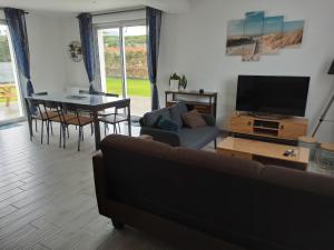 a living room with a couch and a table with a tv at Chez Audrey et Christophe in Saint-Pol-de-Léon