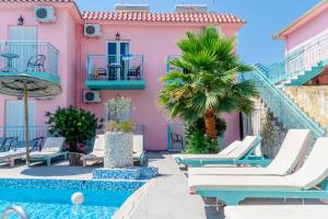 een roze huis met ligstoelen en een zwembad bij Maui in Laganas