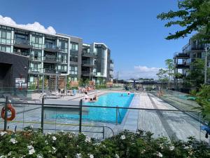 uma piscina com pessoas nela com edifícios em King & Queen Bed, Pool, Firepit, Fully Stocked em Innisfil