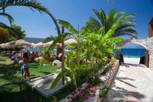 a group of people on a beach with palm trees and flowers at Happy Camp Mobile Homes in Camping Karavomilos Beach in Sami