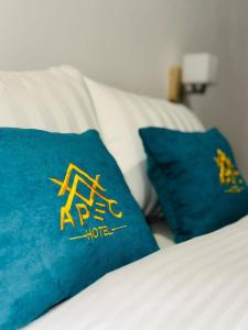 Una cama con dos almohadas azules encima. en Apec Hotel, en Atyraū