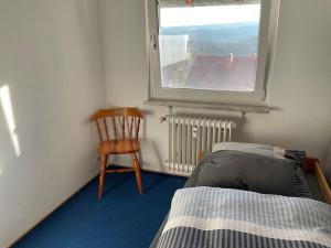 1 dormitorio con 1 cama, 1 silla y 1 ventana en Ferienwohnung zur Alten Schmiede, en Lenzkirch
