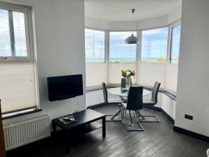 a living room with a table and chairs and windows at The Seafront Apartment - Westbrook Bay Beach - By Goldex Coastal Breaks in Kent