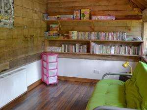 a room with a couch and shelves of dvds at Romden Barn in Smarden