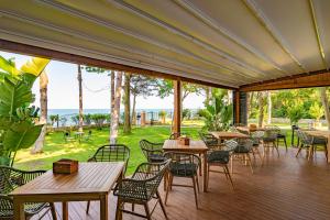 eine Terrasse mit Tischen und Stühlen und Meerblick in der Unterkunft Epico Seafront & Garden Apartments in Olimp