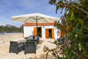 a patio with chairs and an umbrella in front of a building at Holiday home Ambi for 6, heated pool near Trogir in Trogir
