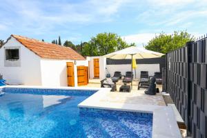 a swimming pool with an umbrella next to a house at Holiday home Ambi for 6, heated pool near Trogir in Trogir