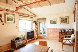 a living room with a wooden table and a television at Mareka Pension in Jeju