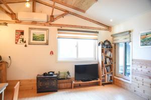 a living room with a television and a book shelf at Mareka Pension in Jeju