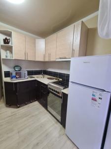 a kitchen with wooden cabinets and a white refrigerator at Район Юбилейный - Боулинг in Karagandy