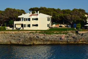 a white house on the shore of the water at Apartamento Tramuntana 3 in Cala Blanca