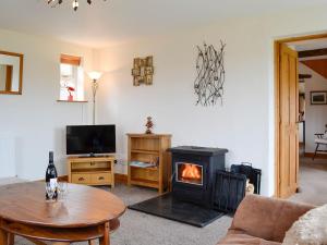 a living room with a fireplace and a table at Farm Cottage in Cleator